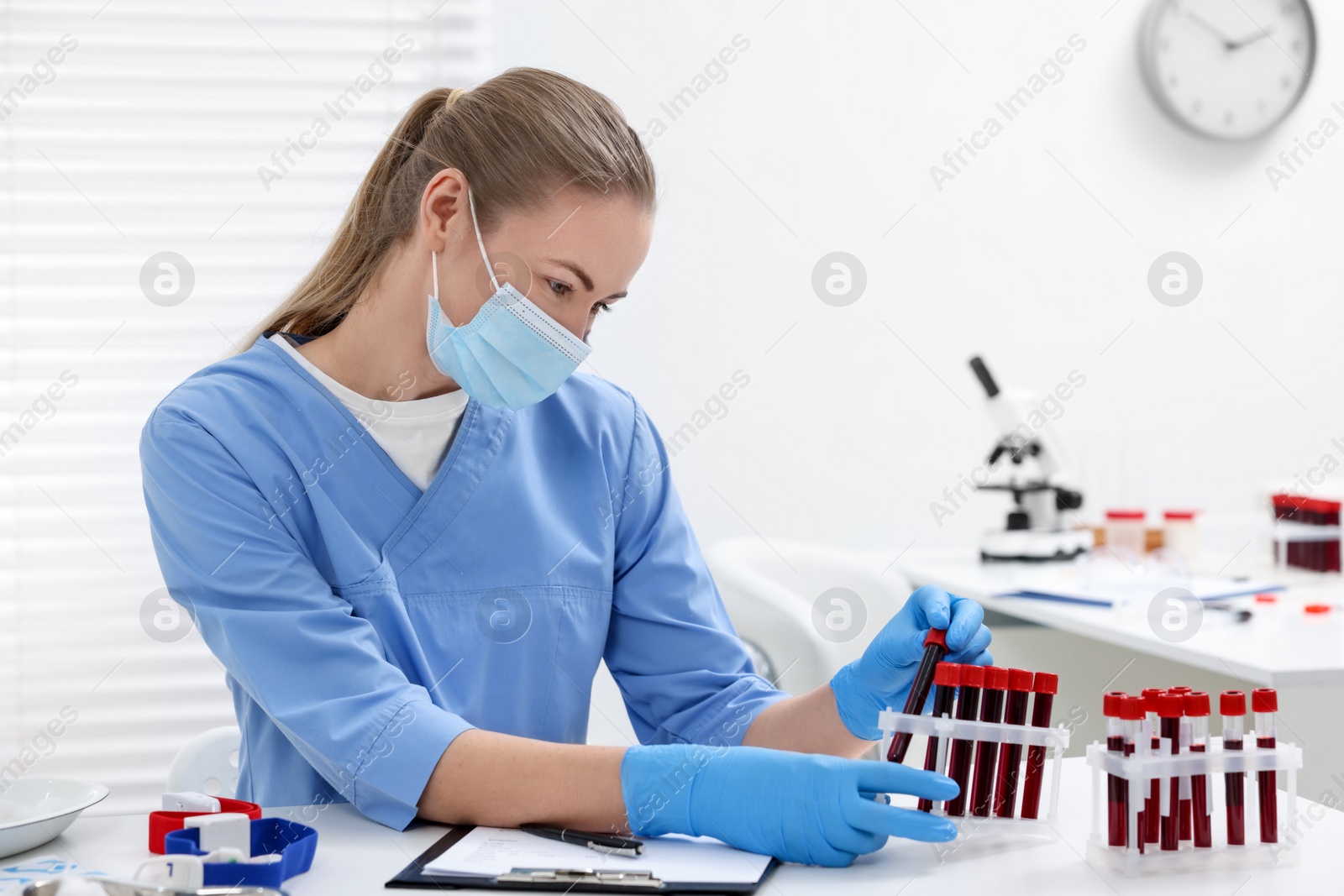 Photo of Laboratory testing. Doctor with blood samples in tubes at white table indoors