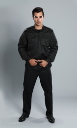 Male security guard in uniform on grey background