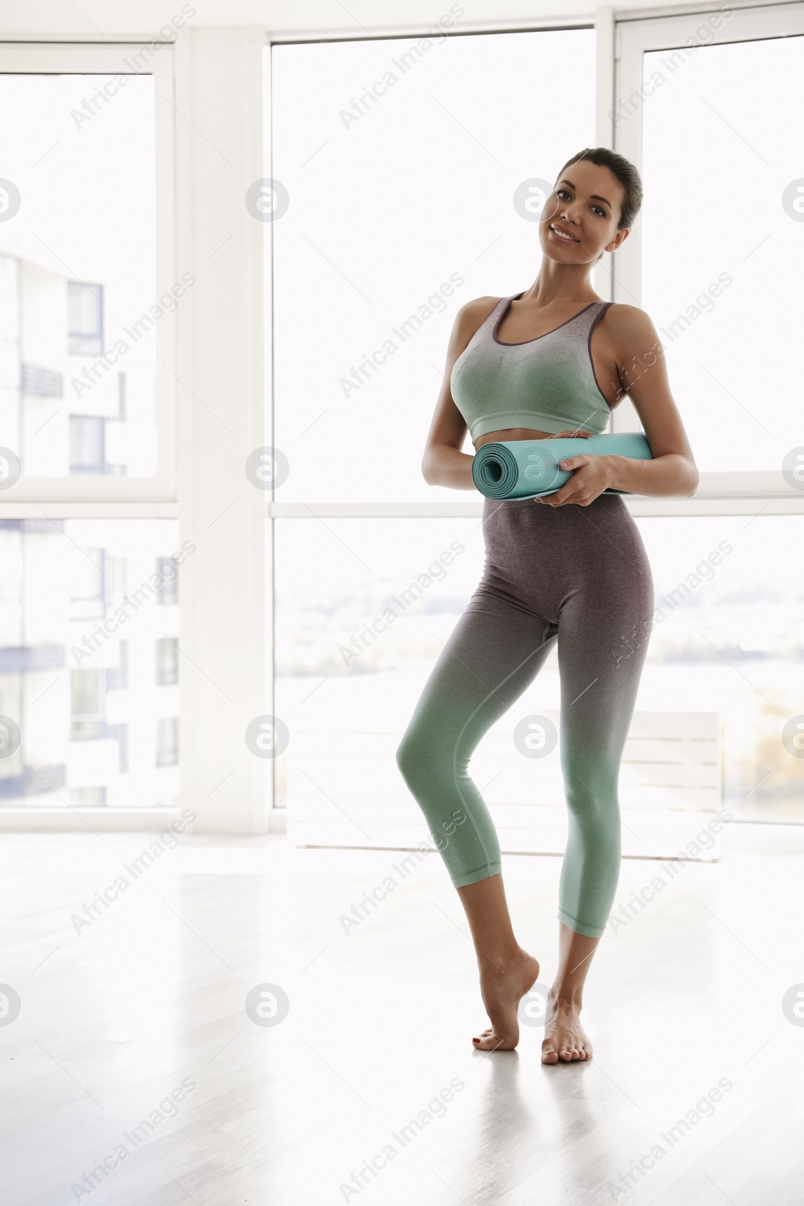 Photo of Young woman with yoga mat in light gym