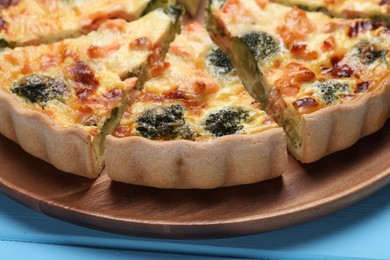 Photo of Delicious homemade quiche with salmon and broccoli on wooden board, closeup