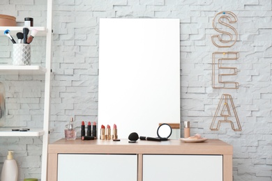 Photo of Decorative cosmetics and tools on dressing table near mirror in makeup room