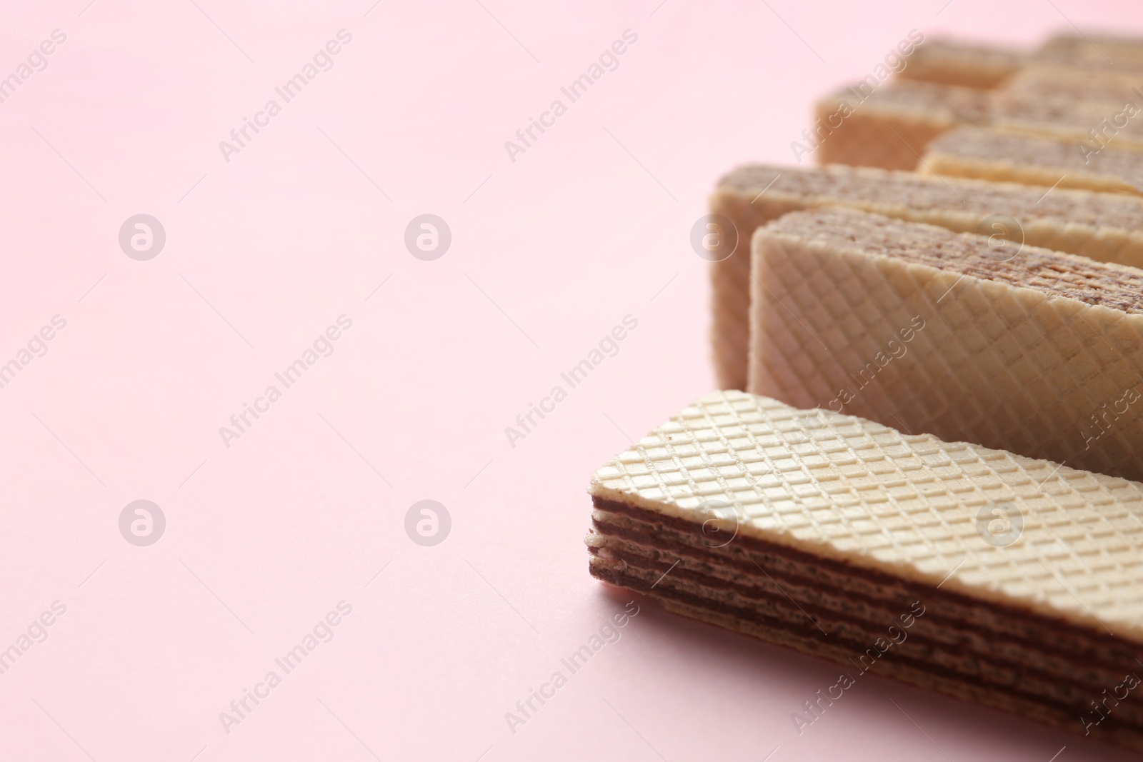 Photo of Tasty wafer sticks on pink background, closeup with space for text. Sweet food