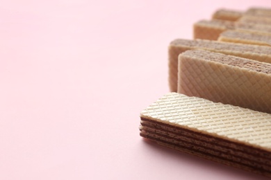 Tasty wafer sticks on pink background, closeup with space for text. Sweet food