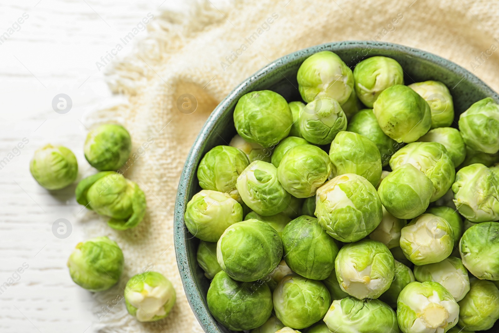 Photo of Bowl of fresh Brussels sprouts and napkin on wooden background, top view