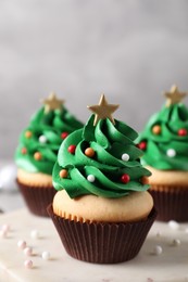 Photo of Christmas tree shaped cupcakes on marble board, closeup