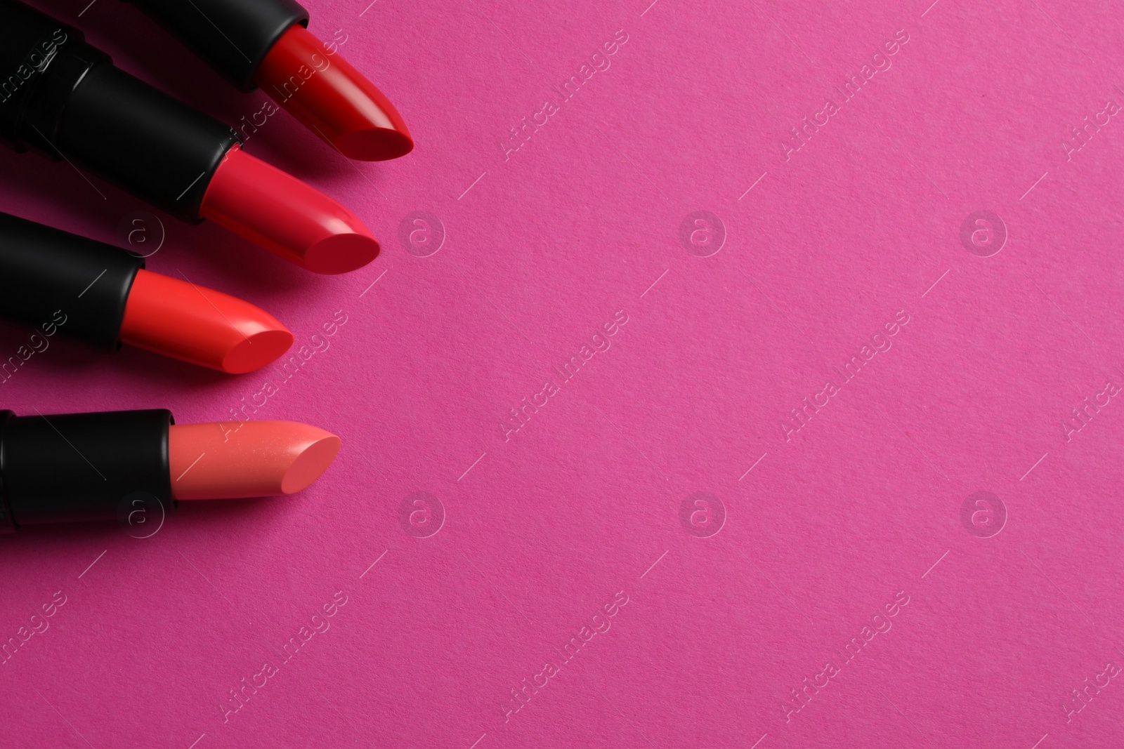 Photo of Beautiful lipsticks on pink background, flat lay. Space for text