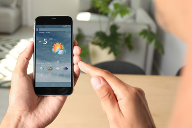 Image of Man using weather forecast app  on smartphone indoors, closeup