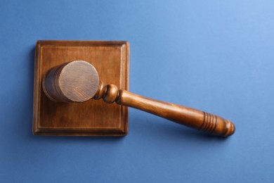 Photo of Wooden gavel and sound block on blue table, top view