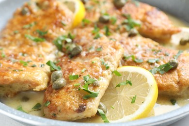 Photo of Delicious chicken piccata with herbs and lemons in pan, closeup