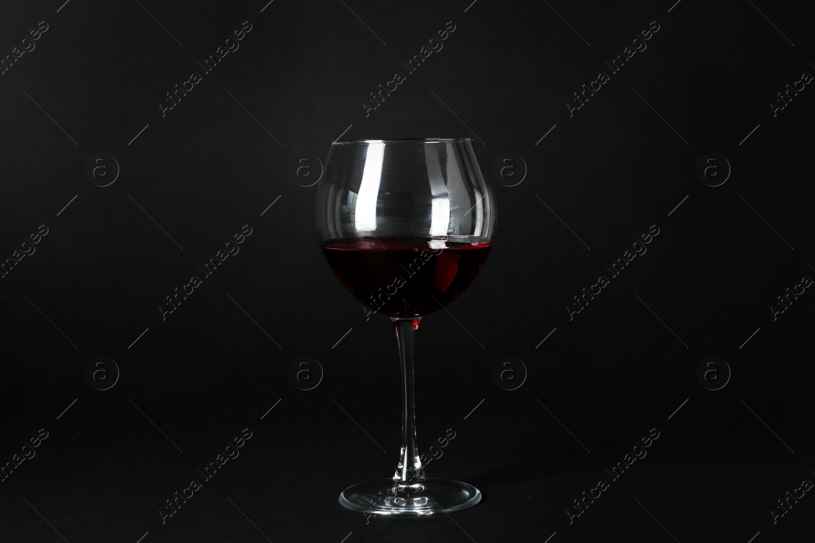 Photo of Glass of expensive red wine on dark background