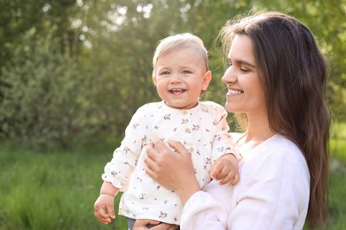 Happy mother with her cute baby in park on sunny day, space for text