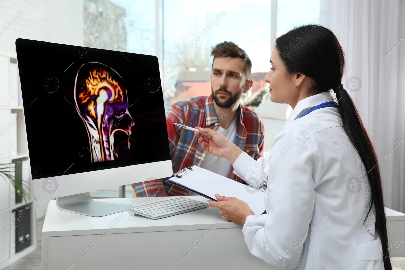 Photo of Neurologist showing brain scan to patient in clinic