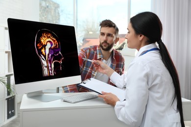 Photo of Neurologist showing brain scan to patient in clinic