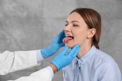Doctor in medical gloves examining woman`s oral cavity indoors, closeup