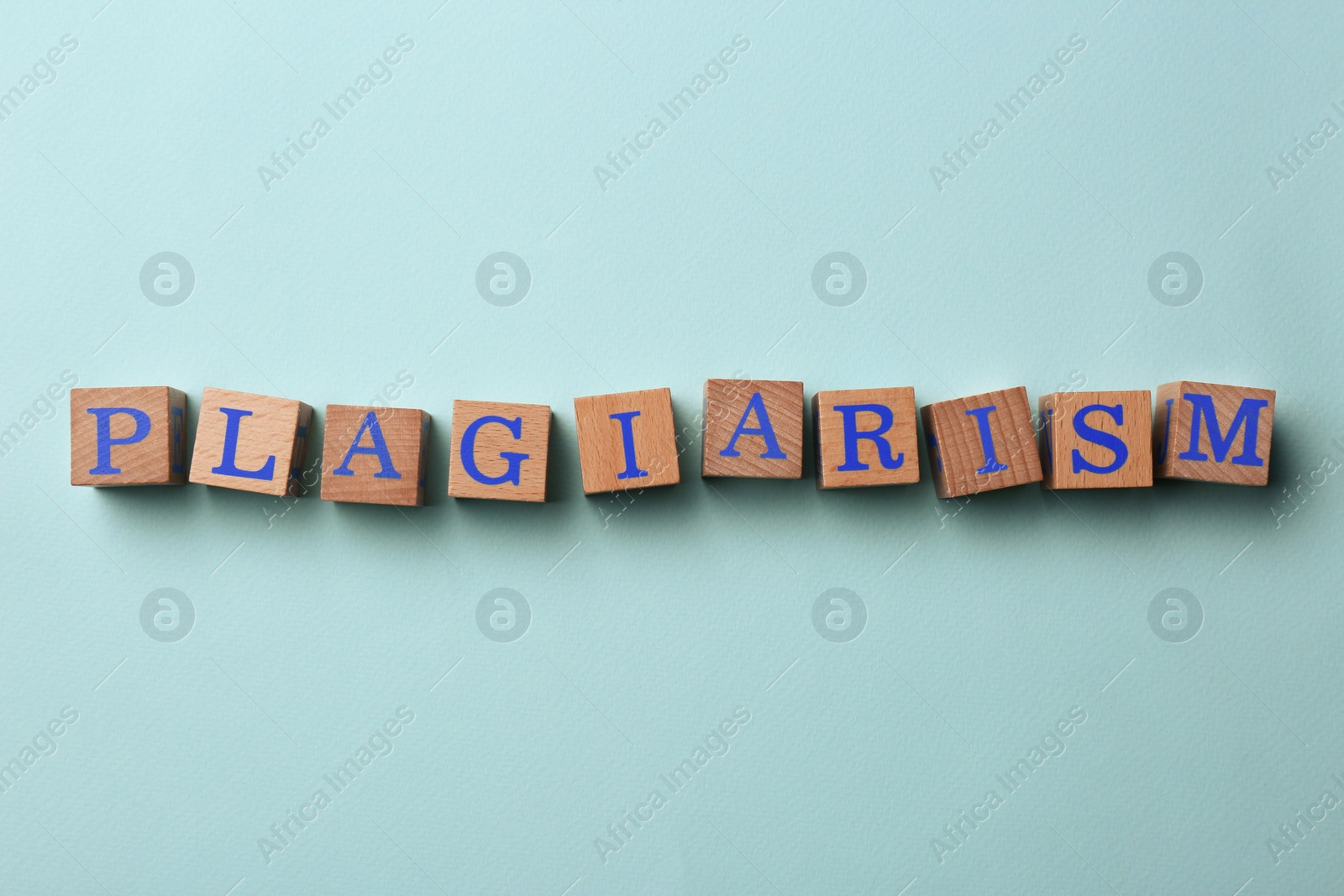 Photo of Wooden cubes with word Plagiarism on turquoise background, flat lay