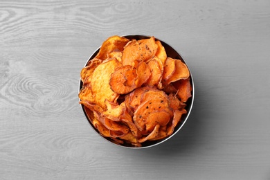 Bowl of sweet potato chips on grey table, top view