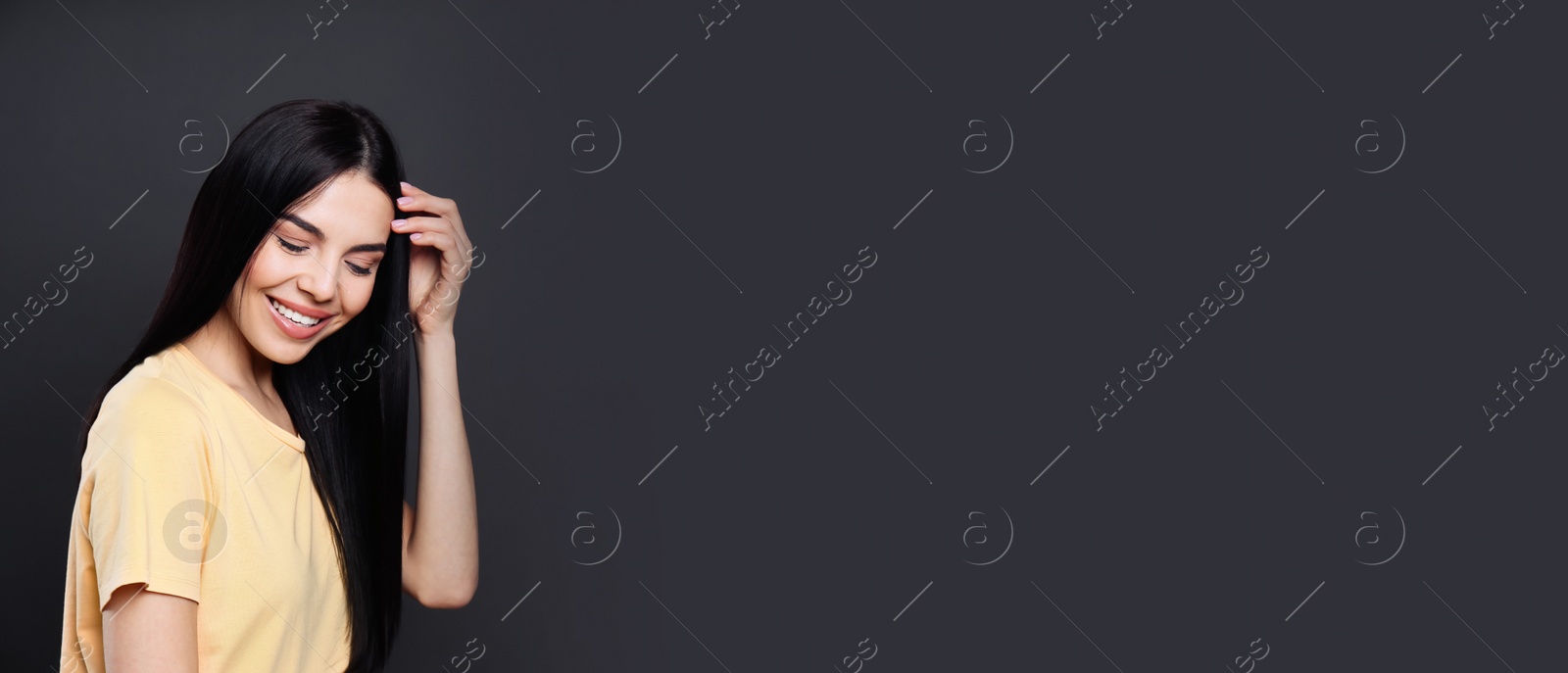 Photo of Portrait of happy young woman with beautiful black hair and charming smile on dark background, space for text