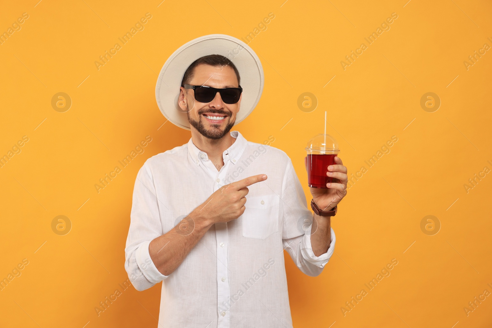 Photo of Man holding plastic cup of delicious juice on orange background