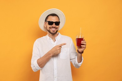 Man holding plastic cup of delicious juice on orange background