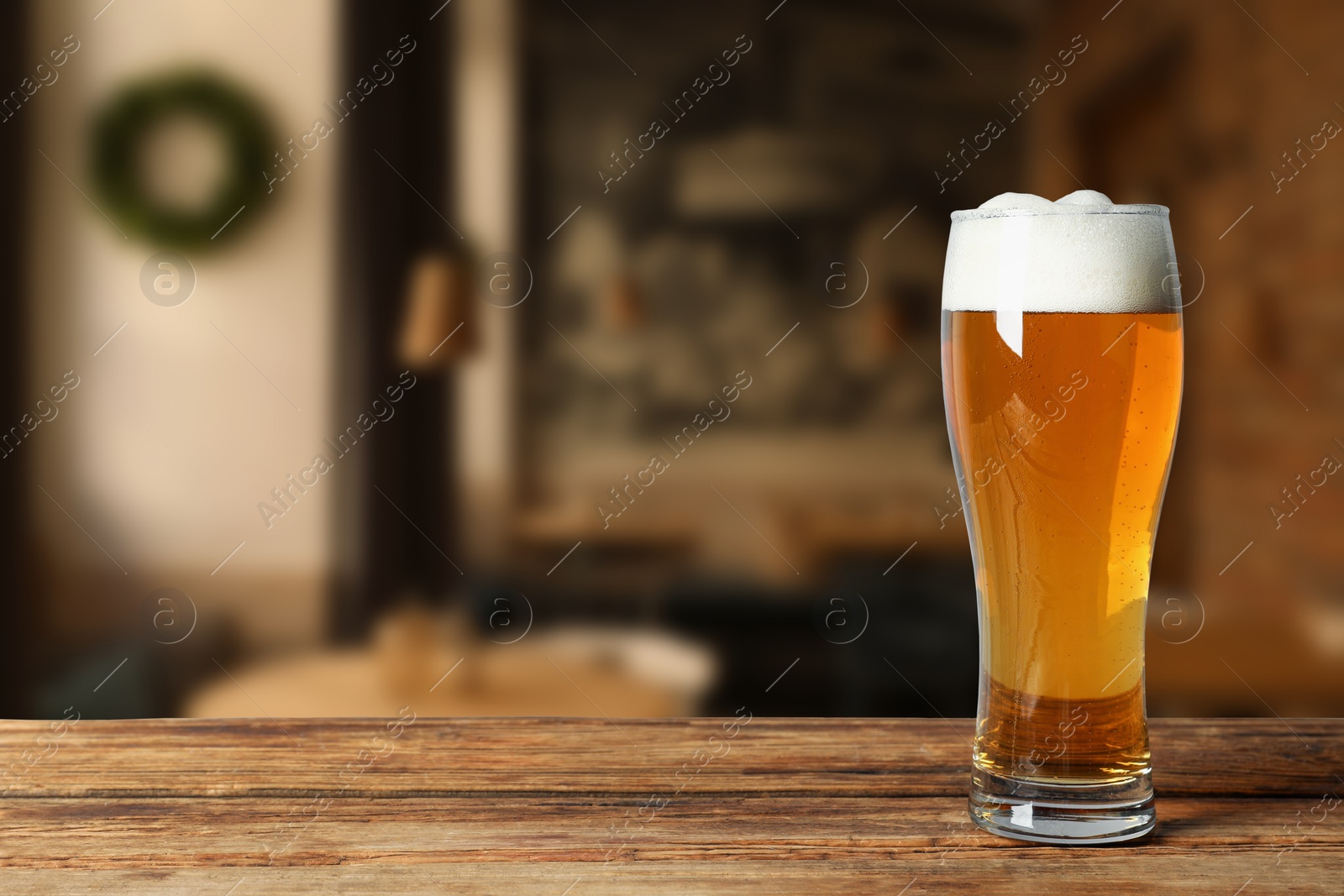 Image of Glass with fresh beer on wooden table in pub, space for text