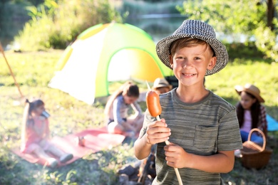 Photo of Little boy with fried sausage outdoors. Summer camp