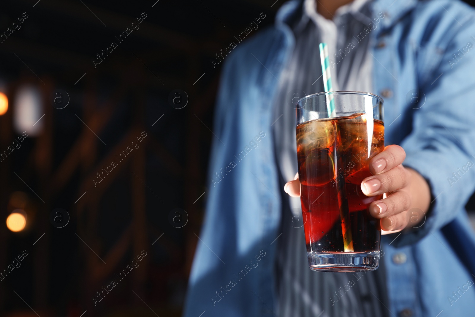 Photo of Woman with glass of refreshing cola indoors, closeup. Space for text