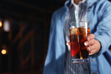 Photo of Woman with glass of refreshing cola indoors, closeup. Space for text