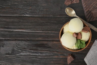 Photo of Delicious vanilla ice cream with chocolate and mint served on wooden table, flat lay. Space for text