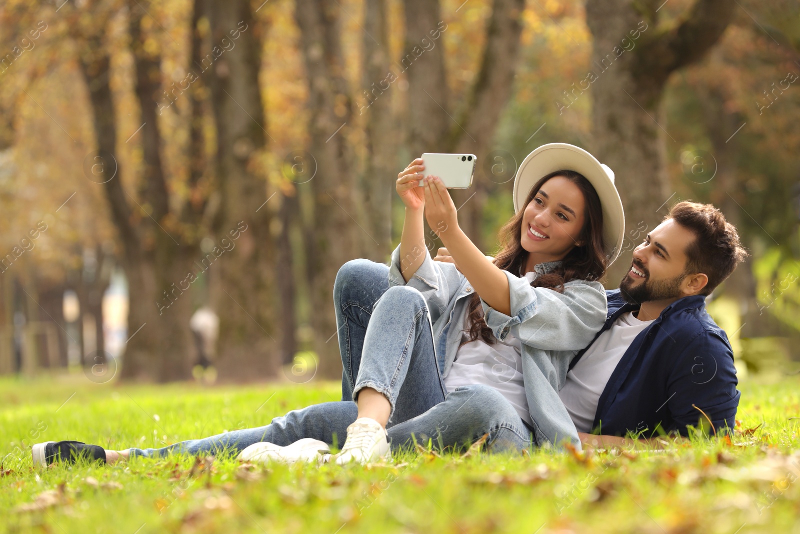 Photo of Beautiful young couple taking selfie in park. Space for text