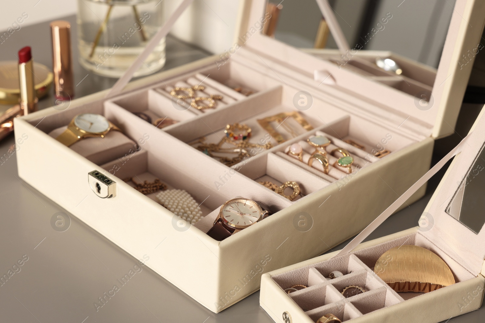 Photo of Elegant jewelry boxes with expensive wristwatches and beautiful bijouterie on grey table