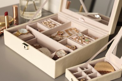 Photo of Elegant jewelry boxes with expensive wristwatches and beautiful bijouterie on grey table