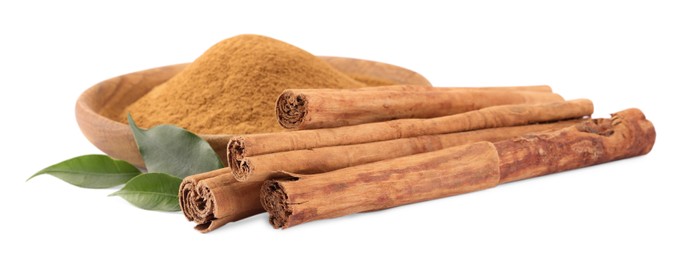 Photo of Dry aromatic cinnamon sticks, powder and green leaves isolated on white