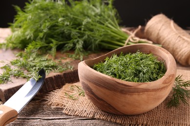 Photo of Fresh dill, cutting board and knife on wooden table