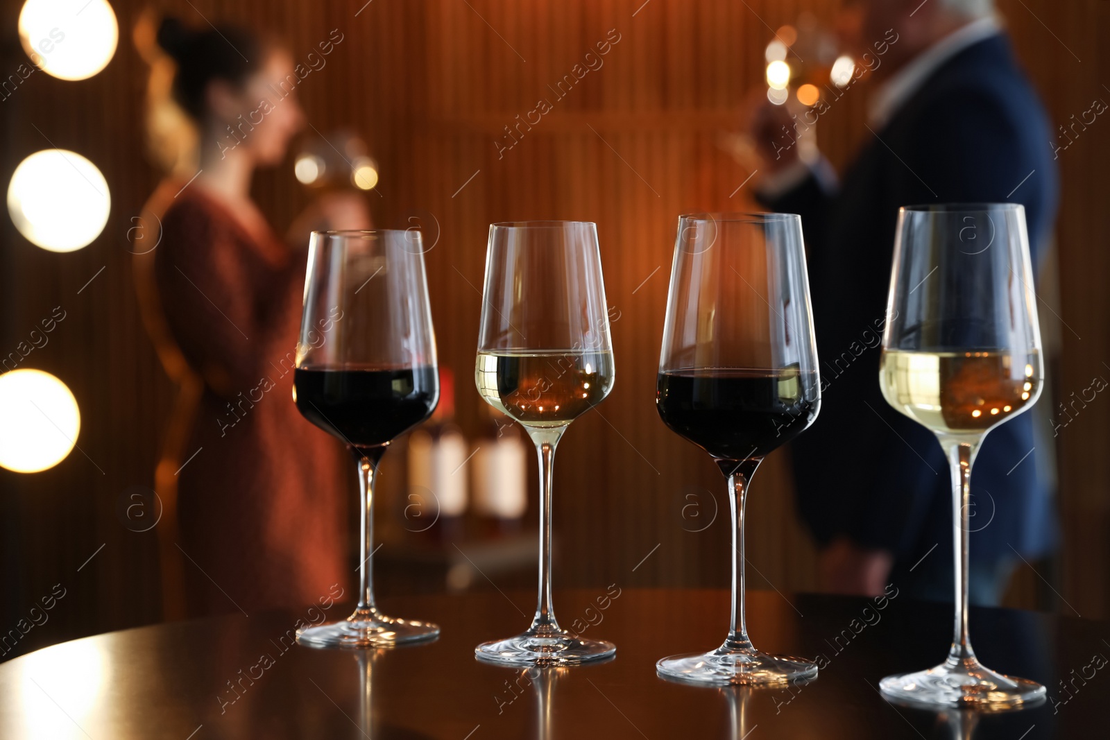 Photo of Glasses of different wines on table against blurred background