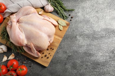 Fresh raw chicken with spices and vegetables on grey textured table, flat lay. Space for text