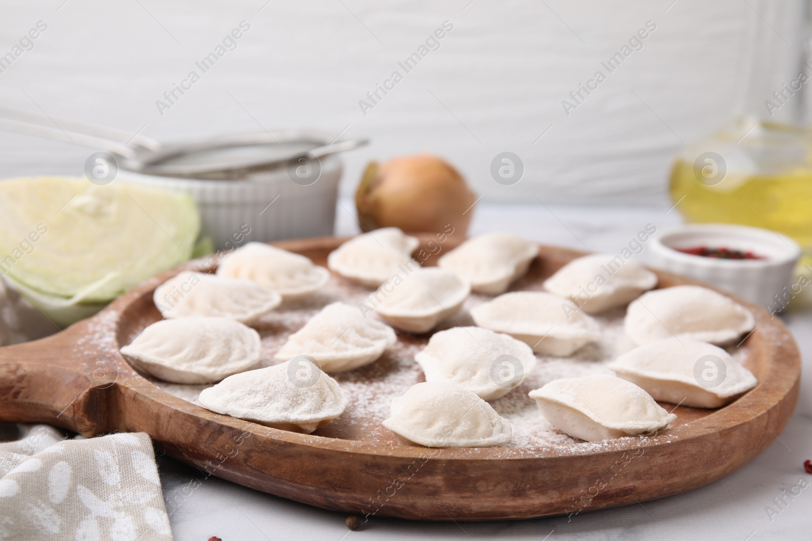 Photo of Raw dumplings (varenyky) with tasty filling and flour on wooden board, closeup