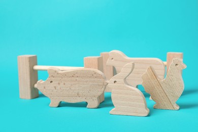 Photo of Wooden animals and fence on light blue background. Children's toy