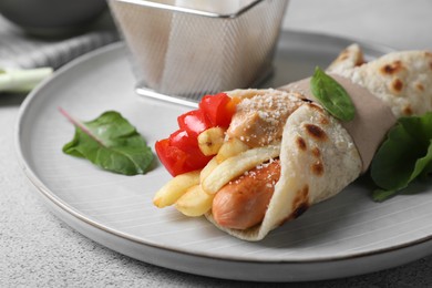 Photo of Delicious pita wrap with sausage, french fries and pepper on light gray table, closeup