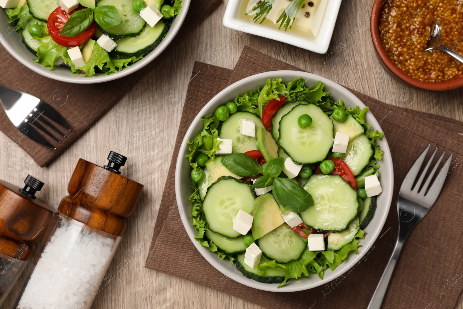 Photo of Tasty fresh salad with cucumber served on wooden table, flat lay