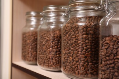 Photo of Glass jars with coffee beans on rack, space for text
