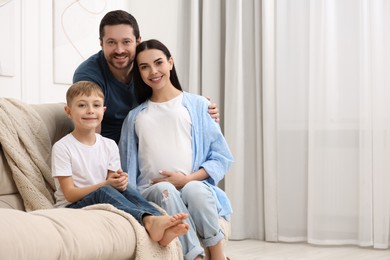 Portrait of happy pregnant woman with her son and husband at home, space for text