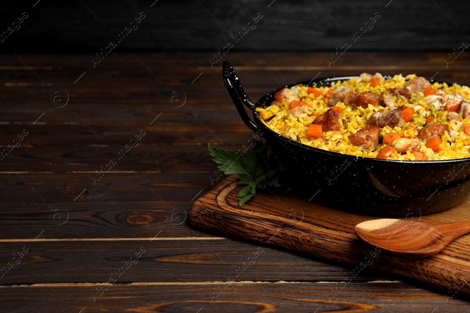 Photo of Delicious pilaf with meat and carrot served on wooden table. Space for text