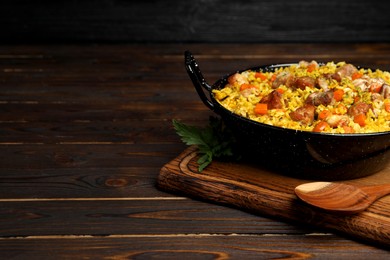 Delicious pilaf with meat and carrot served on wooden table. Space for text