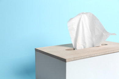 Holder with paper tissues on light blue background, closeup