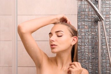 Beautiful young woman taking shower at home