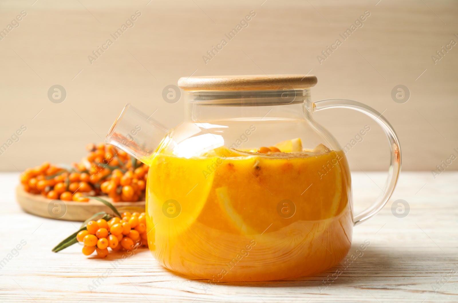 Photo of Delicious sea buckthorn tea with orange slices and fresh berries on white wooden table