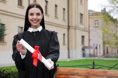 Photo of Happy student with diploma after graduation ceremony outdoors. Space for text