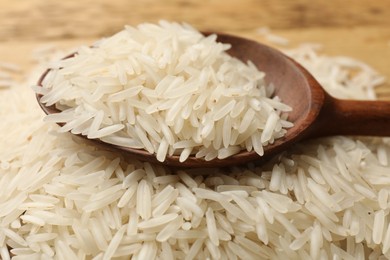 Photo of Raw basmati rice with wooden spoon on table, closeup