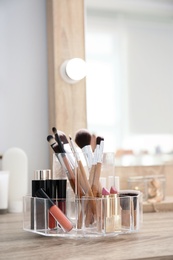 Photo of Organizer with cosmetic products for makeup on table near mirror