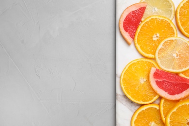 Cut citrus fruits on grey table, top view. Space for text